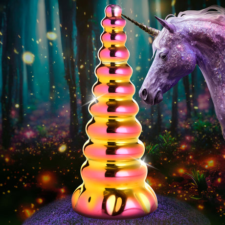 Creature Cocks Twilight Rainbow Unicorn Glass Dildo with iridescent pink and yellow-gold design in a magical forest setting.