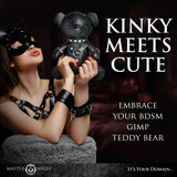 Master Series Gimp Teddy Bear Black held by a model in bondage attire, showcasing a unique blend of charm and alternative styling.