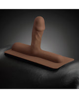 The Cowgirl Bronco Silicone Attachment Chocolate resting on a black surface, showcasing its realistic design and texture.