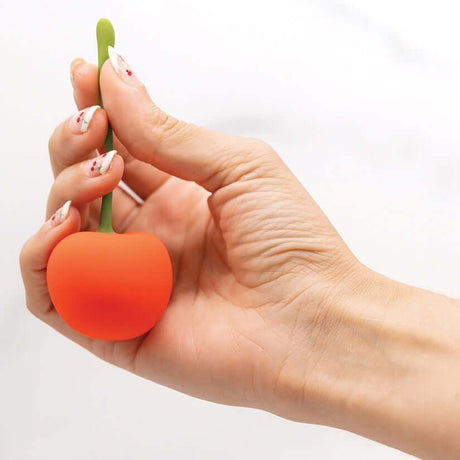 A hand holding The Official Cherry Emoji Vibrator, showcasing its playful cherry design and functional shape.