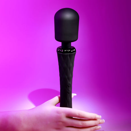 Playboy Royal Silicone Vibrating Wand Massager Black held in hand against a vibrant purple background.