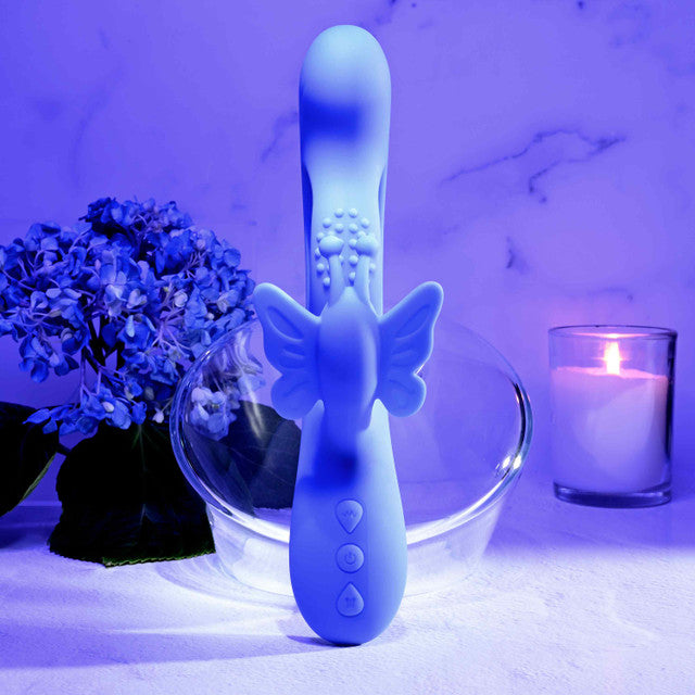 Evolved Butterfly Dreams Silicone Rabbit Vibrator displayed with floral elements and candle ambiance.