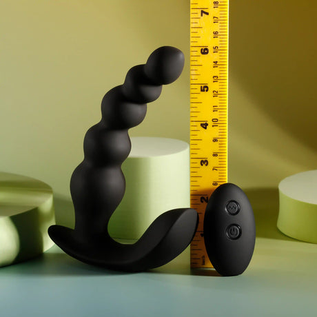Evolved Bead Me Up Silicone Vibrating Anal Beads Black with measurement ruler against a soft background.