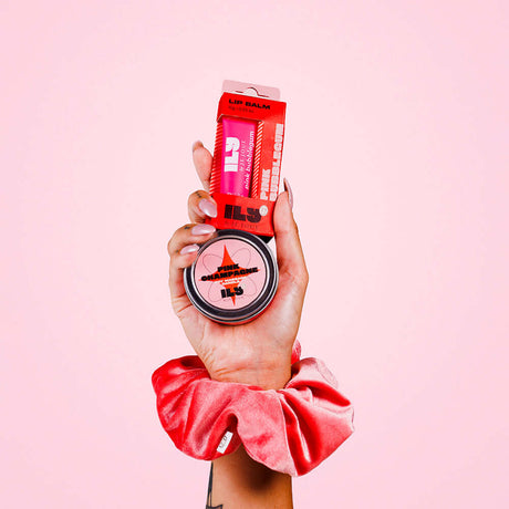 Ily By Je Joue Pink Bubblegum Lip Balm 0.35 Oz displayed in hand with packaging against a pink background.