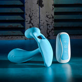 Gender X Wear Me Out Wearable Dual Vibrator Blue next to its remote control on a blue surface.