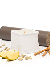 Jimmyjane Natural Massage Oil Candle 4.5 Oz Santal displayed with lemon and spices on a yoga mat.