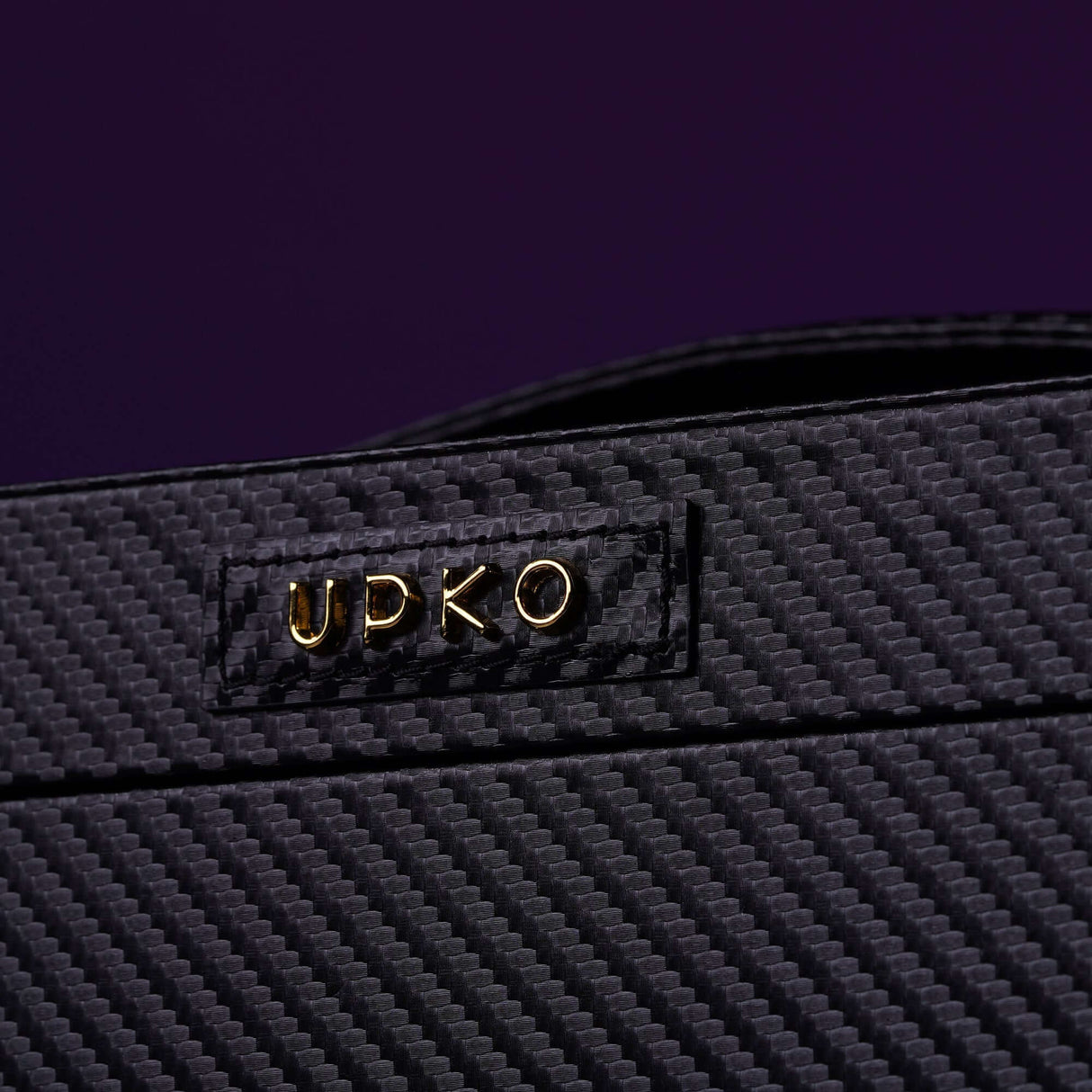 Close-up of UPKO logo on luxurious black leather bondage tools case with textured design.