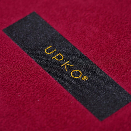 Close-up of UPKO logo on luxurious red fabric, showcasing quality craftsmanship of bondage tools set.