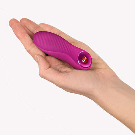 Fun Factory Bijou Bullet Vibrator Magenta held in a hand, showcasing its compact design and textured surface.