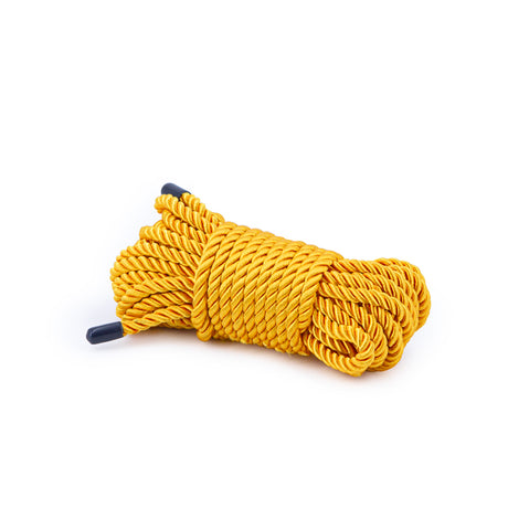 Bondage Couture 25 Feet Polyester Rope Gold displayed in a sleek, coiled form, showcasing its vibrant metallic finish.