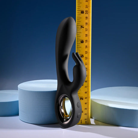 Playboy Late Night Bunny Silicone Rabbit Vibrator Black next to a ruler and foam discs for size reference.