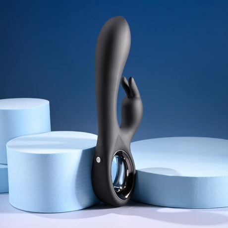 Playboy Late Night Bunny Silicone Rabbit Vibrator Black displayed against a blue backdrop with foam circles.