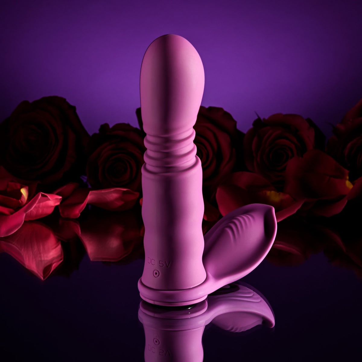 Playboy Match Play Silicone Dual Vibrator Purple surrounded by red roses on a reflective surface.