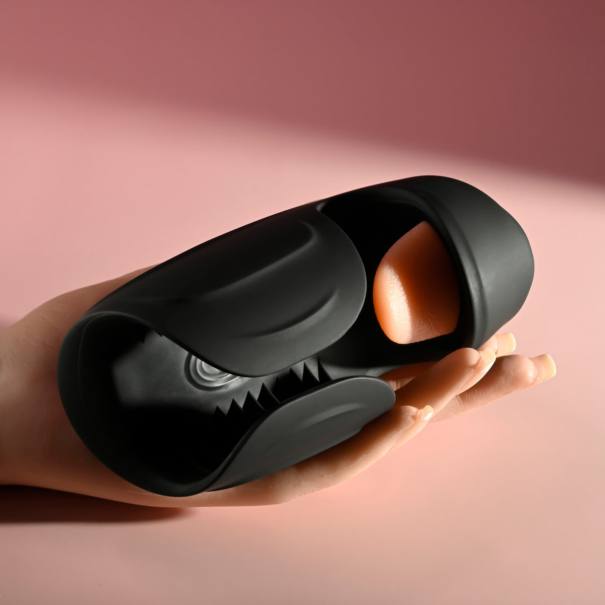 Lick the Tip Vibrating Tongue Stroker Black resting in a hand against a soft pink background.