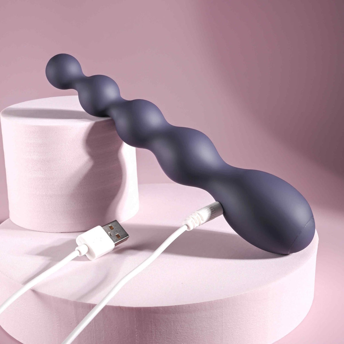 Zero Tolerance Rumpy Bumpy Silicone Anal Beads Purple on a pink display with USB charging cable.