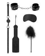 Shots Ouch Introductory Bondage Kit No 4 Black, featuring handcuffs, a ball gag, blindfold, paddle, and feather tickler.