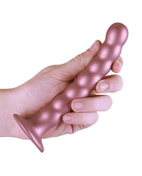 Shots Ouch 6.5 inch Beaded G-Spot Dildo Rose Gold held in a hand, showcasing its elegant design and beaded texture.