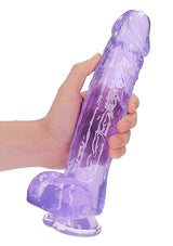 Realrock Realistic Dildo with Balls 10 inch Purple held in hand, showcasing translucent purple design and realistic features.
