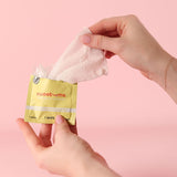 Person holding Sweetums Pina Colada Flavored Intimate Wipes packaging with a wipe partially pulled out.