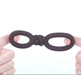 Maia Cooper Liquid Silicone Dual Super Stretch C-Ring Brown displayed in hands, showcasing its unique design and flexibility.