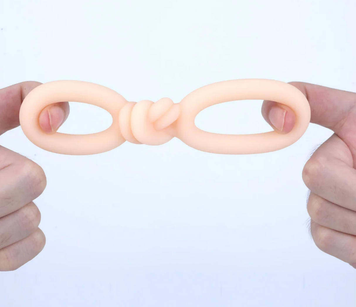 Maia Cooper Liquid Silicone Dual Super Stretch C-Ring Beige being held, showcasing its ultra-stretchy design.
