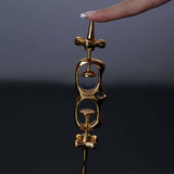 UPKO Thumb Metal Cuffs held by a hand, showcasing their sleek gold design and unique restraint mechanism.
