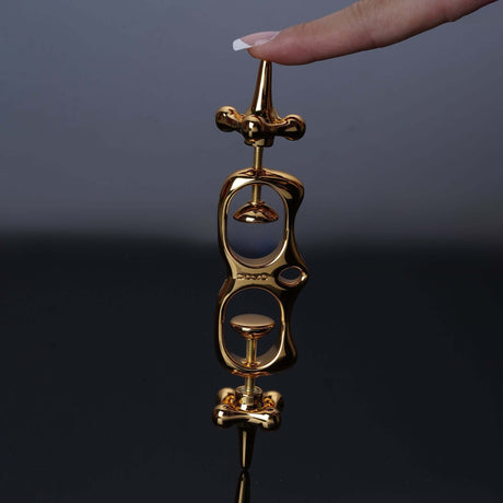 UPKO Thumb Metal Cuffs held by a hand, showcasing their sleek gold design and unique restraint mechanism.