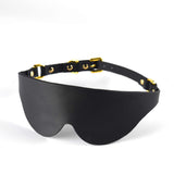 Black leather eye mask with gold hardware, part of a premium BDSM kit for enhanced sensory play.