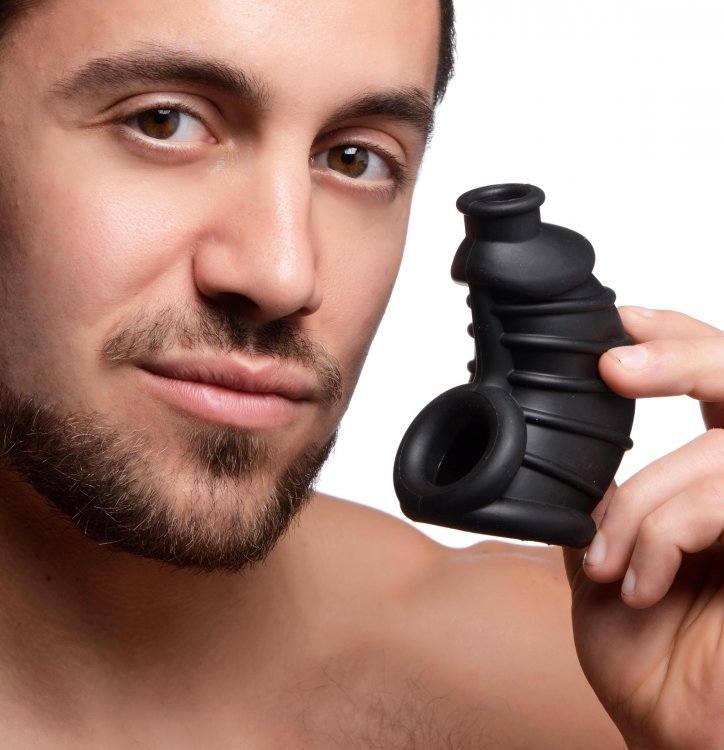 Master Series Dark Chamber Silicone Chastity Cage held by a man showcasing its flexible silicone design.