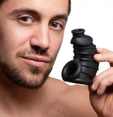 Master Series Dark Chamber Silicone Chastity Cage held by a man showcasing its flexible silicone design.