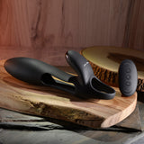 Zero Tolerance Nautilus Vibrating Penis Sleeve Black on wooden surface with remote control.