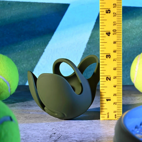 Zero Tolerance Nutty Buddy Vibrating Cock Ring Green on a surface next to a measuring tape and tennis balls.
