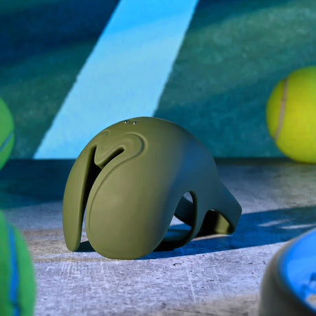 Zero Tolerance Nutty Buddy Vibrating Cock Ring Green on a textured surface with tennis balls in the background.