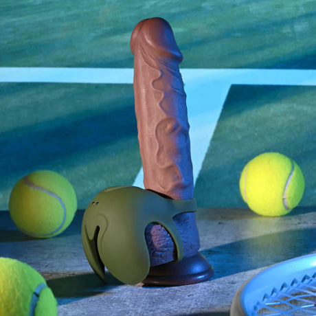 Zero Tolerance Nutty Buddy Vibrating Cock Ring Green displayed beside tennis balls and a playful background.