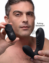 Man holding Alpha Pro 7X P-Thump Tapping Prostate Stimulator and remote, showcasing pulsing sensation feature.