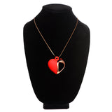 10X Vibrating Silicone Heart Necklace displayed on a black stand, featuring a red silicone heart and rose gold accents.
