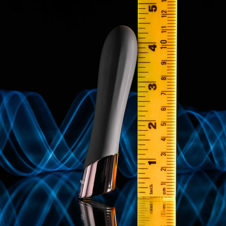 Evolved Back In Black Rechargeable Silicone Bullet beside a measuring tape, showcasing its sleek design and chrome tip.