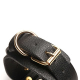 Close-up of a black vegan leather cuff with a gold buckle, part of the Bedroom Bliss Lover's Restraints Set.