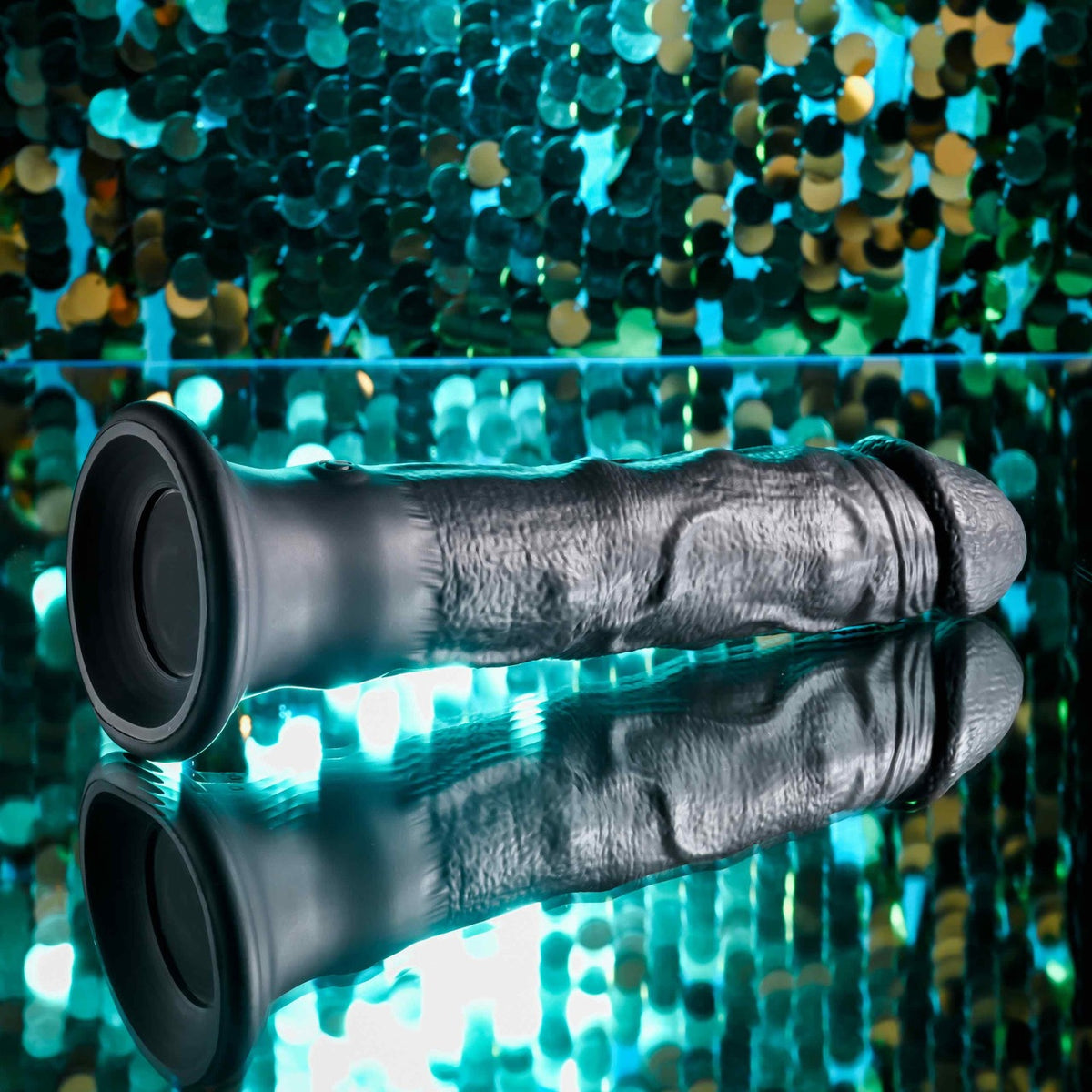 Evolved Black Thunder Vibrating Silicone Dildo Remote on reflective surface with sparkling background.