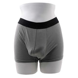 Gender X 4 Inch TPE Packer Dildo Vanilla shown with supportive gray packer shorts on a mannequin.